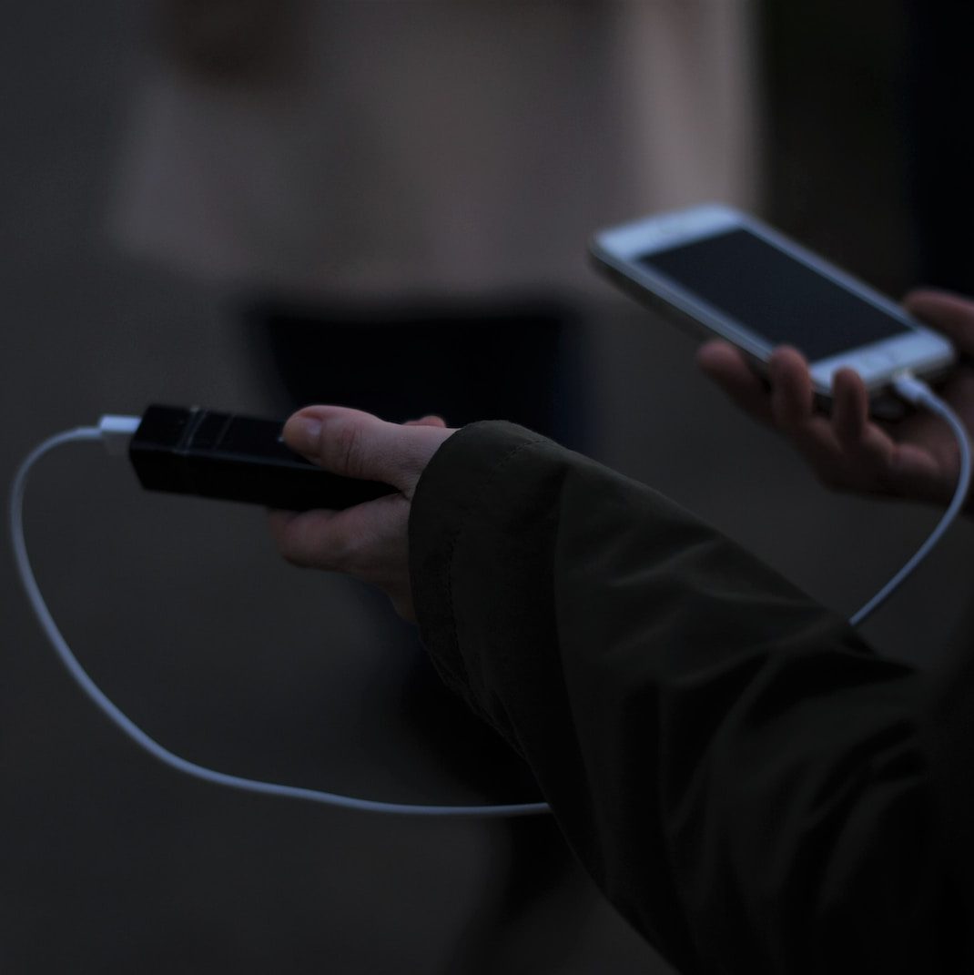 a person holding a cell phone and a charger