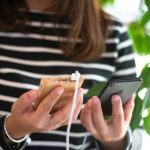 woman in black and white striped long sleeve shirt holding silver iphone 6