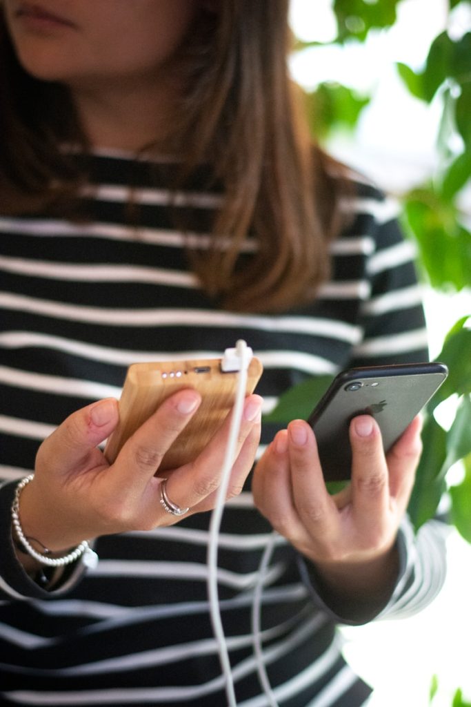 woman in black and white striped long sleeve shirt holding silver iphone 6