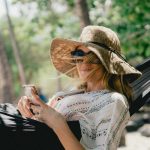 woman lying on black hammock while holding phone